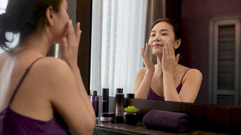 Woman applying brightening serum in bathroom